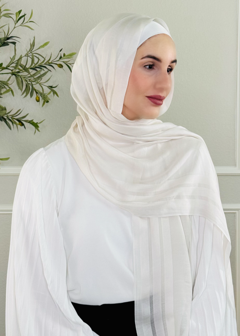 Woman wearing a white hijab in a neutral setting