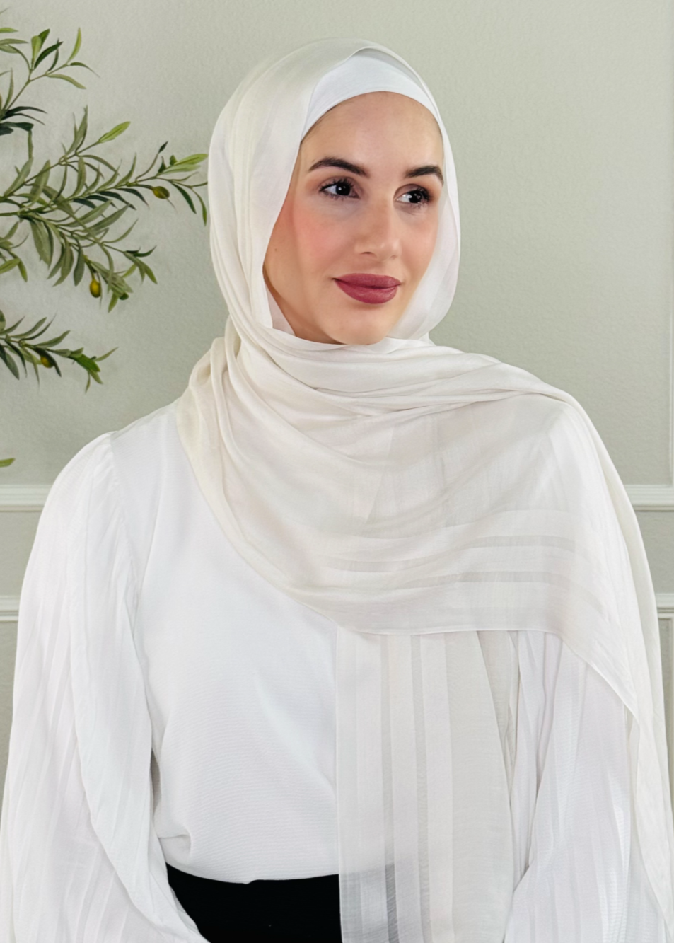 Woman wearing a white hijab and white top in a minimalistic setting